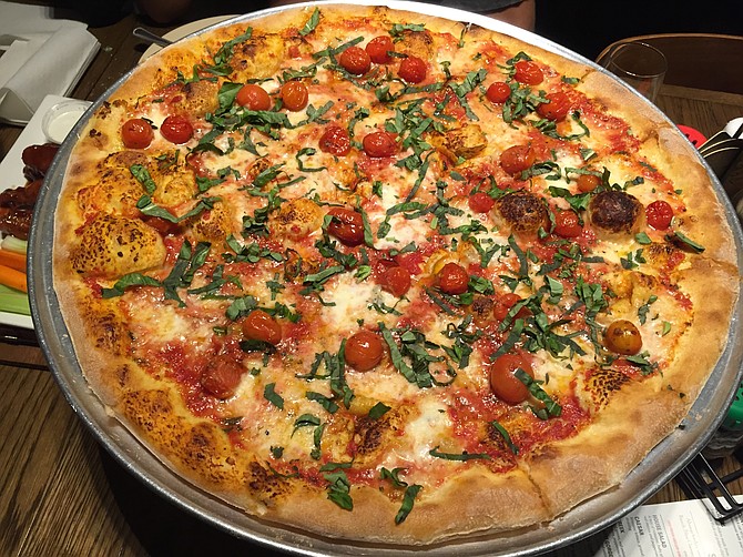 The New York–style Margherita pizza is topped with roasted cherry tomatoes.