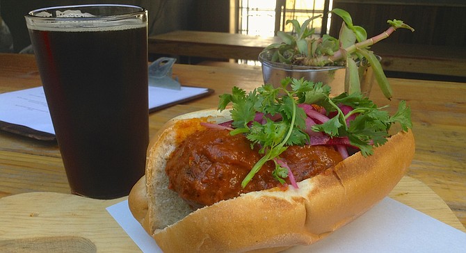 Beef-and-bacon meatball sandwich with chipotle sauce and a brown ale