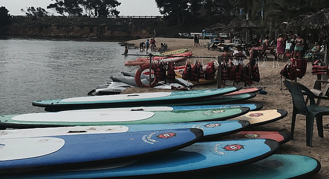 Paddleboards stacked on Carlsbad Lagoon's beach. 