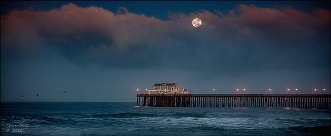 The full moon setting behind the Oceanside pier at sunrise.