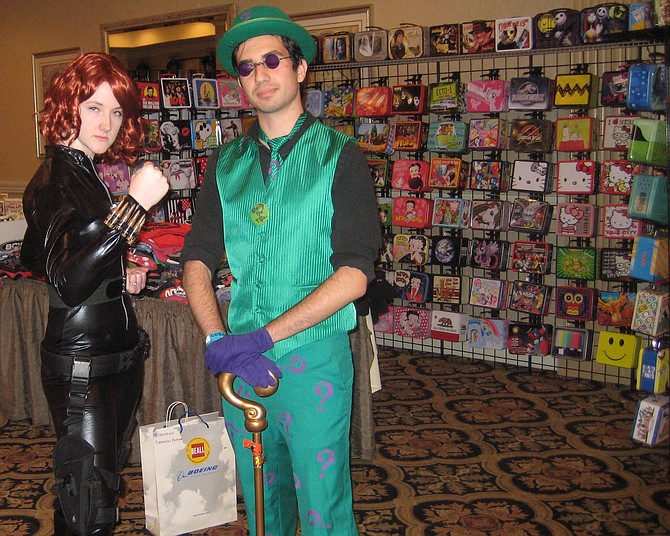 Erin Reilly (Black Widow) and Michael Pogrebinsky (Riddler) are in front of Star Force Collectibles booth