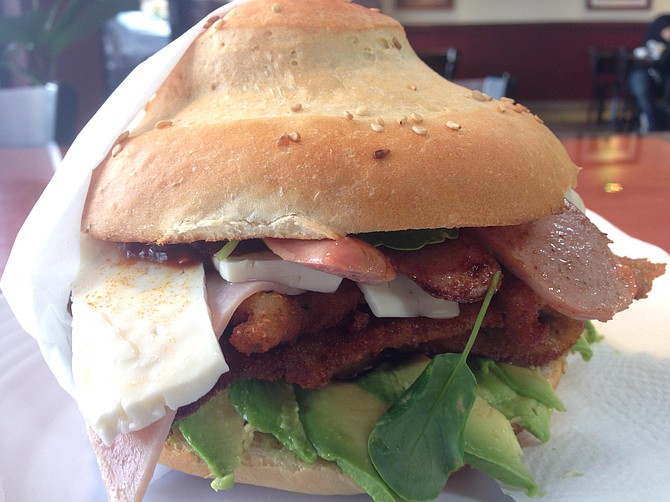 This Cubano Cemita features breaded pork, ham, and sausage with avocado, panela cheese, and papalo leaves.