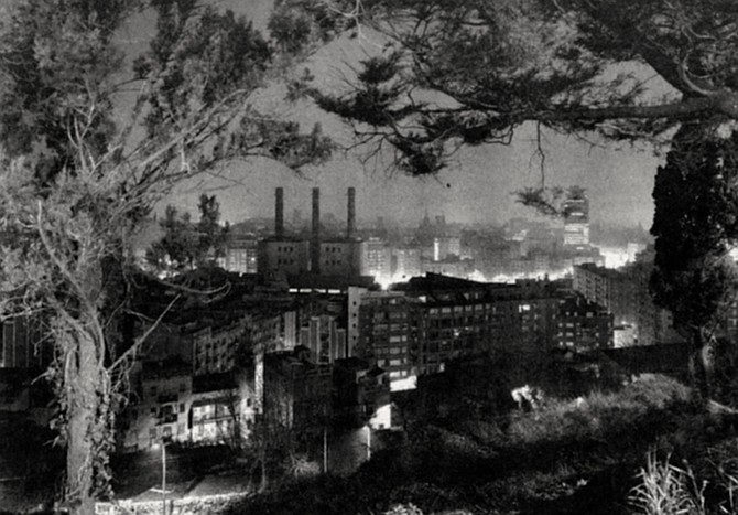 Barcelona Through the Trees, 1982. It’s night. Seen from a high vantage point, through a framing wreath of trees, the city looks as if it’s on fire.  - Image by Philipp Scholz Rittermann