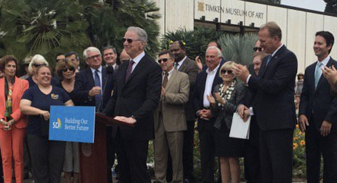 June 30, 2016, in Balboa Park: Irwin Jacobs at the lectern, Faulconer applauding behind him, former mayor Jerry Sanders between (without the tie)