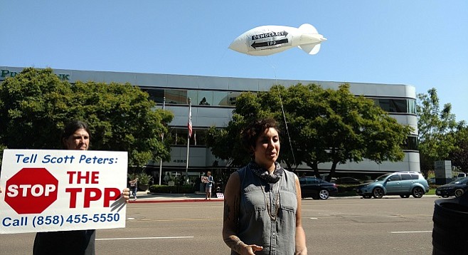 Anti-TPP activists Lizzy Jean and Chris McKay outside Scott Peters' La Jolla office. Others across the street fly a blimp denouncing the proposed trade agreement.