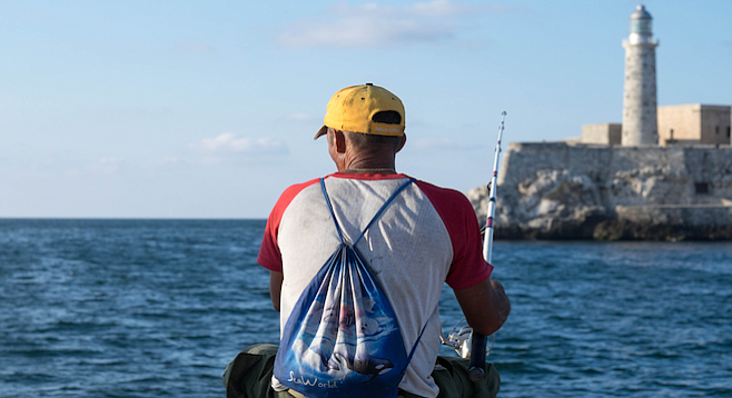 Havana fisherman on the malecón sports a SeaWorld backpack.