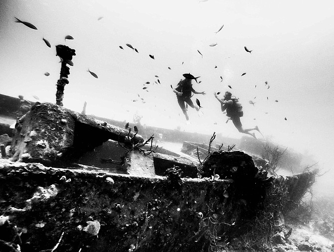 Diving buddies share a moment of magic, hovering over the wreck of an American battleship.