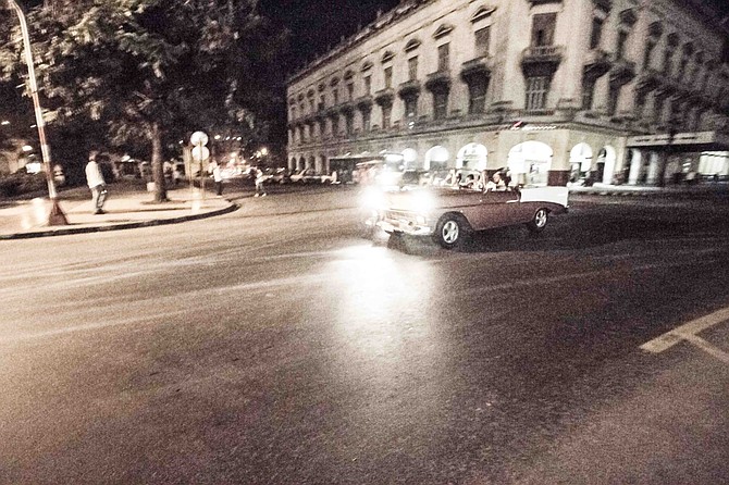 A classic rolls through the hot, Havanan night.