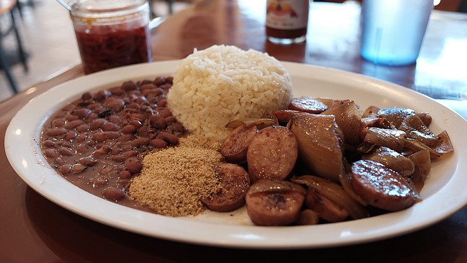 A Prato Feito calabrasa acebolado —aka the combo plate —  with beans, rice, yucca flour, sliced sausage, and onions.