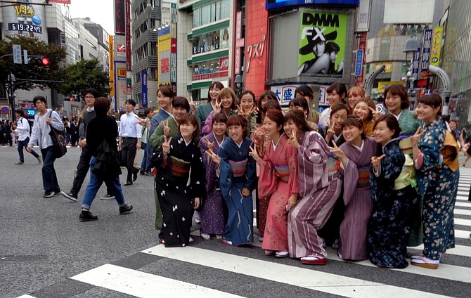 Young girls wearing kimonos and flashing v-sign in Shibuya Crossing