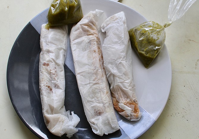 Three burritos wrapped in paper — bean and cheese, desebrada, steak and potatoes
