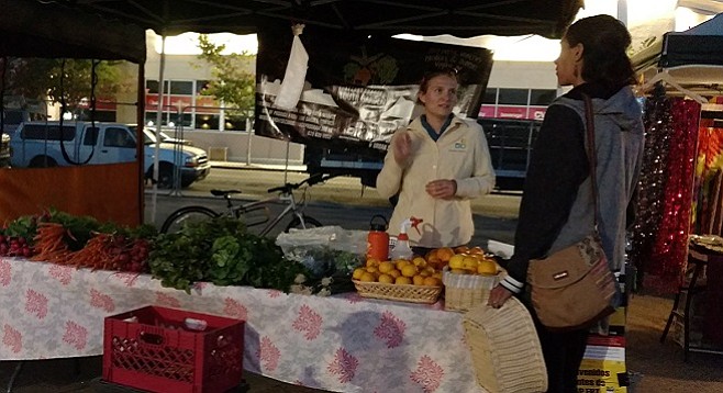 Kristin Kvernland interacts with a customer of the Second Chance Youth Garden farmers' market stand