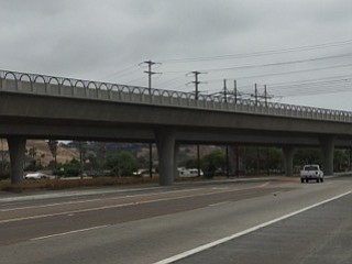 A bridge in Oceanside (between the coast and Mission San Luis Rey) where barely noticeable black chain link fencing is used within each arch but not between the bars.