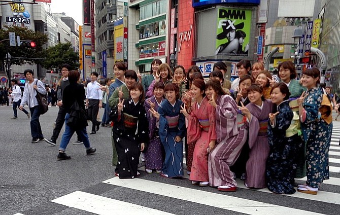 Young girls wearing kimonos and flashing v-sign in Shibuya Crossing.

