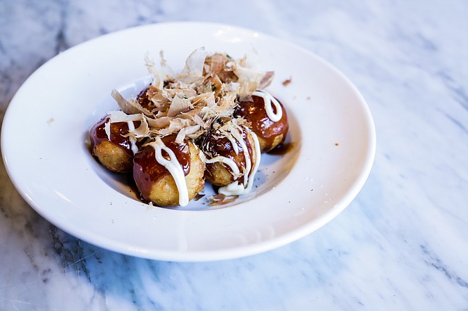 Takoyaki is deep-fried octopus fritters with mayo and brown sauce, topped with bonito (dried fish) flakes.