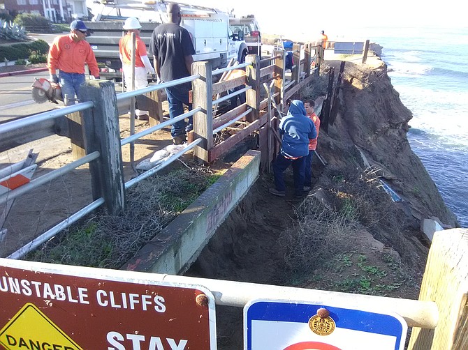 The hole opened up in the foot trail between the street guard rail and the cliff edge.