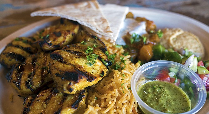 A chicken shish kebab platter, featuring shiraz salad, hummus, basmati rice, and a tomato eggplant stew.