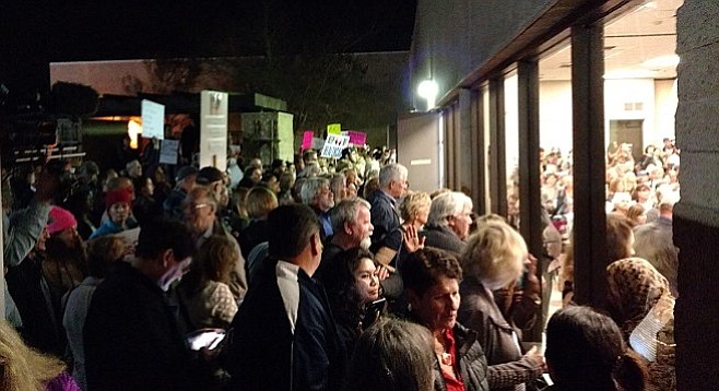 Crowded out of the meeting, many of the protesters gathered at the windows.