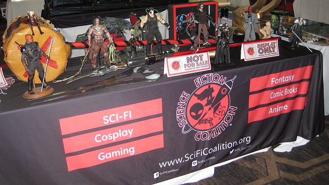 Science Fiction Coalition booth featuring figures of DC Comics characters including Bane, Catwoman and Deathstroke. There is a figures of Darth Vader from Star Wars. 