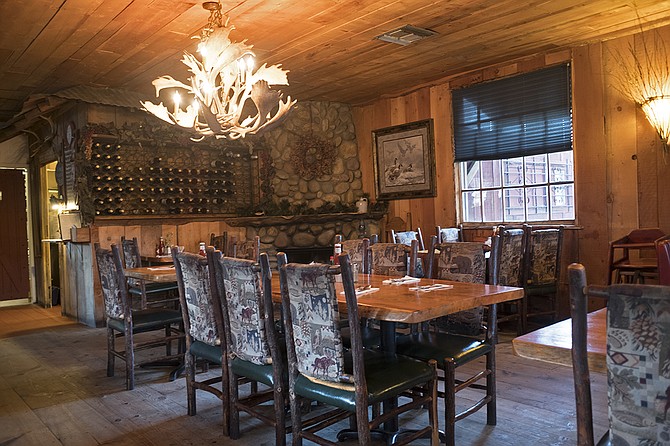The woody dining room features a stone fireplace and deer-antler chandeliers. 