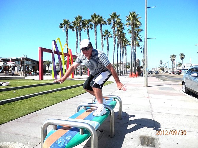 Tourist from Indiana on surfboard bench. Attached to each bench there is a plaque telling the history of big wave surfing in Imperial Beach Sloughs.
