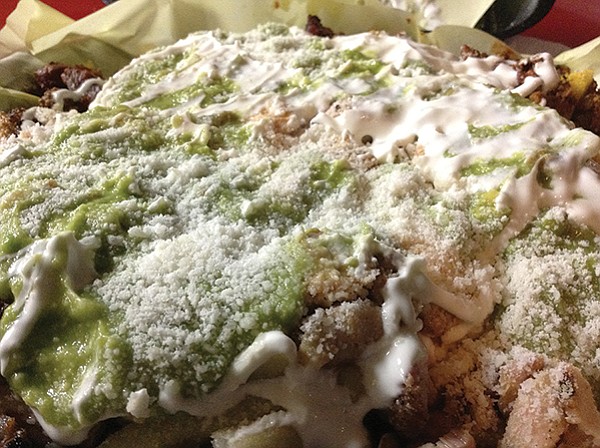 Revo fries: an ocean of guac, crema, and crumbly cheese covers a mountain of sin.