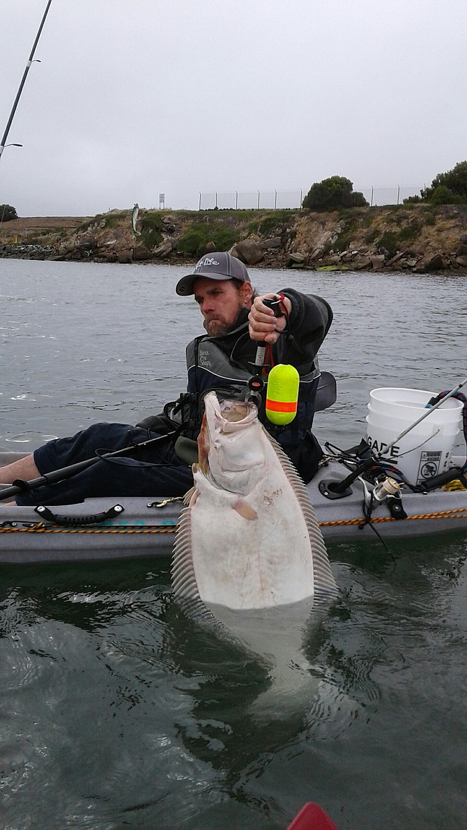 A shot of a friend Chris with a nice 15-pound halibut from off the poles at the seaplane ramps.