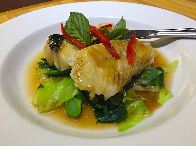 Steamed cod over bok choy in a spicy lime-garlic broth, garnished with peppers and mint leaves