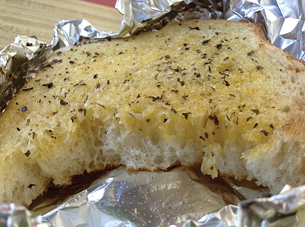 Big, thick, hot chunk with a quarter-inch of soaked butter and garlic, plus basil sprinkled on top.