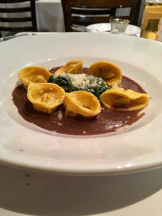The duck tortellini is served with sautéed spinach and parmesan in a generous portion of port-wine sauce