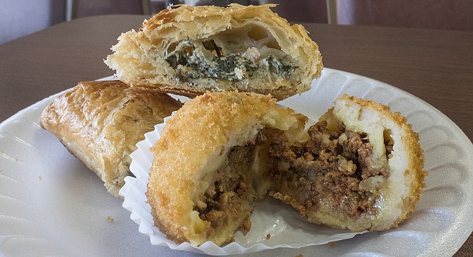 A spinach and cheese empanada, and a papa rellena de carne, cut open.