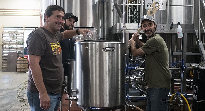 AleSmith owner Peter Zien adds hops to a collaboration beer with Second Chance head brewer Marty Mendiola (right) and assistant brewer Craig Gregovics.