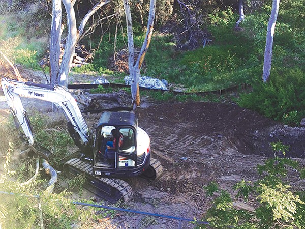 Backhoe driver moves fallen tree