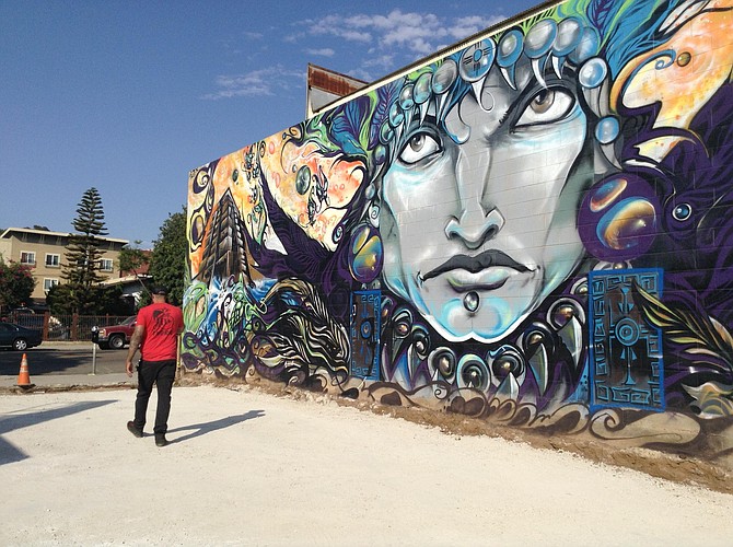 Shawn Buss walks across the spare lot where the patio cafe will go. Mural comes with the property
