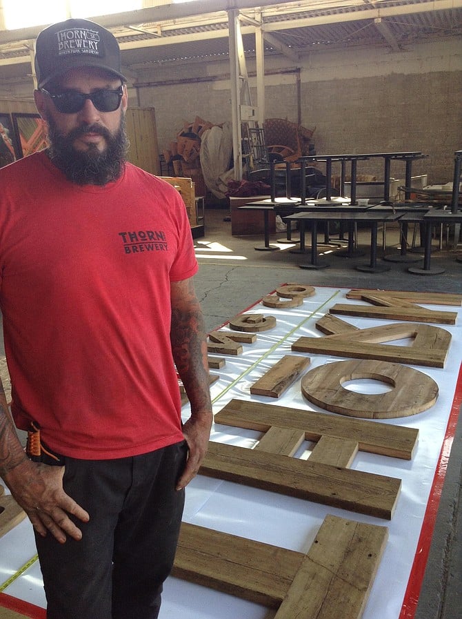 Shawn Buss with the sign he's making from recycled Wisconsin wood