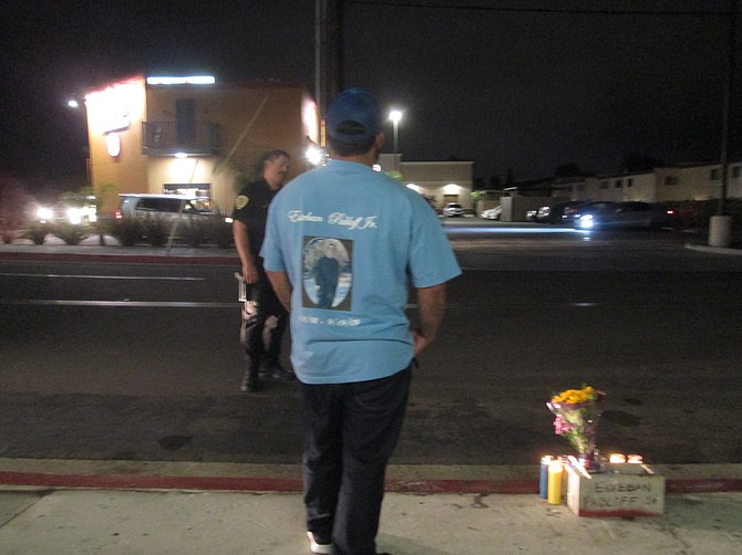 "I raised him from a baby."  Uncle still in mourning after eight years stands by street memorial wearing teeshirt dedicated to the victim.