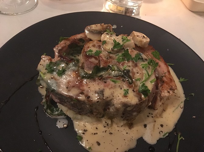 The pork belly roll is wrapped around spinach, mozzarella, and pancetta and served over mashed potatoes.