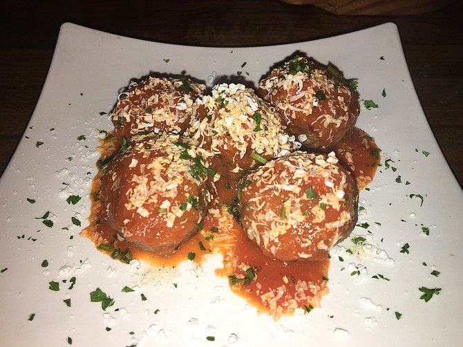 The meatballs are a mix of ground beef and lamb, feta cheese, garlic, onion, and mint. They are served with a red-pepper sauce.