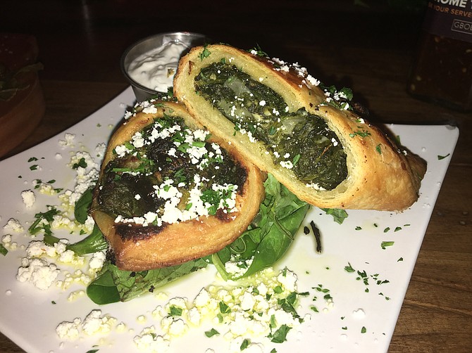 The spanakopita is a pocket sandwich made with crispy puff pastry and filled with a lemon-tinged spinach and feta cheese.