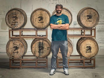 Brewer Kyle Harrop stands before a rack of barrels at his brewery, Horus Aged Ales.