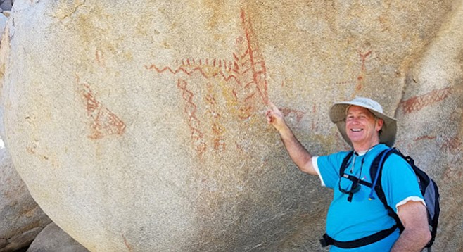 A hiker points out the mysterious pictographs