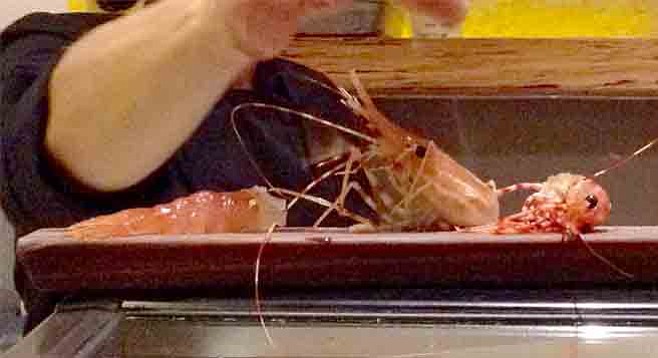 The shrimp, cut in two, head part still alive and gazing upon his cooked abdomen lying in front of him