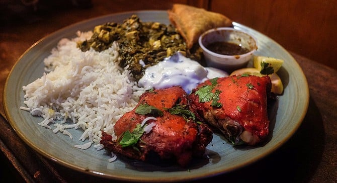 Tandoori chicken thighs, stewed spinach saag, lamb samosa, rice, and condiments; delivered.