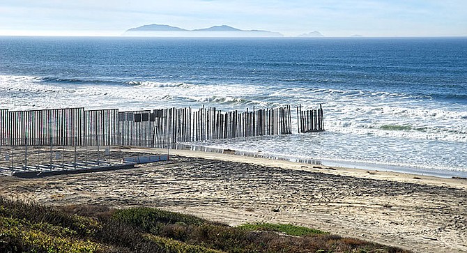 Border Patrol requests San Diego and Imperial Beach Lifeguards for two people holding on to border fence in the water.