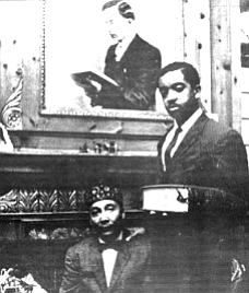 Elijah Muhammad and son Wallace under photo of W.D. Fard