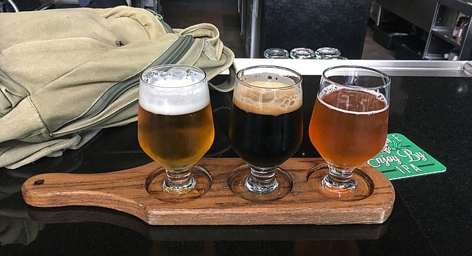A carry-on bag and flight of Stone Hoppy Lager, Cimmerian Portal stout, and I'm Peach double IPA.