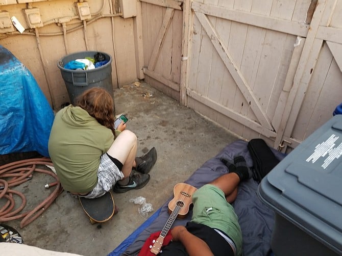 Two men lounging in Nati's garbage storage area in the rear parking lot on Friday. 