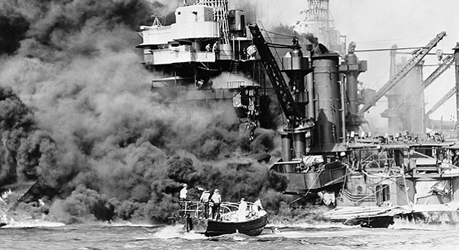 Sailors in a motor launch rescue a man overboard alongside the burning USS West Virginia during or shortly after the Japanese air raid on Pearl Harbor.