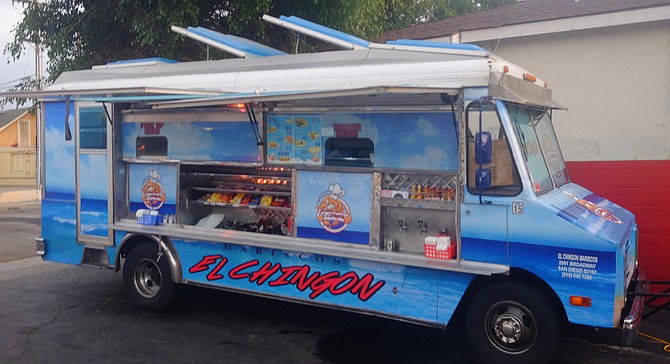 A mariscos truck in the parking lot of a barber shop.