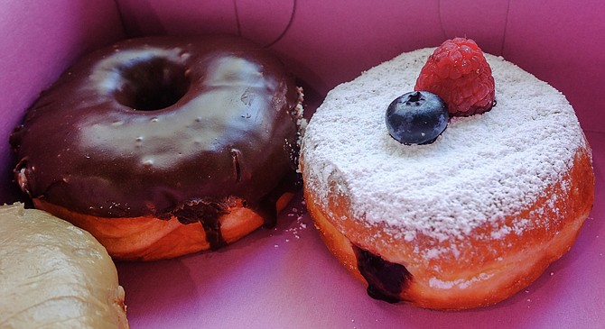 A chocolate ganache raised donut, and mixed berry jelly donut topped with fruit
